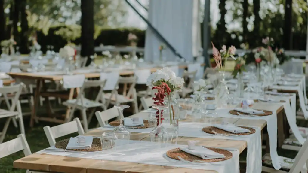 Rectangular tables set with white linen and woven placemats in an outside location