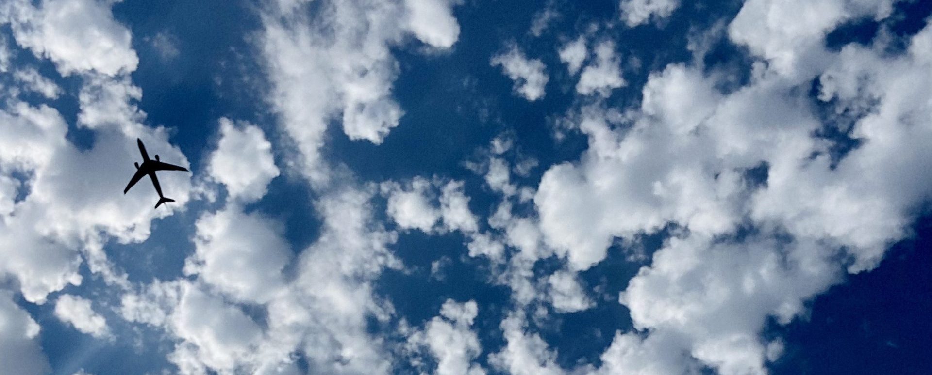 Blue sky and clouds with silhouette of an airplane